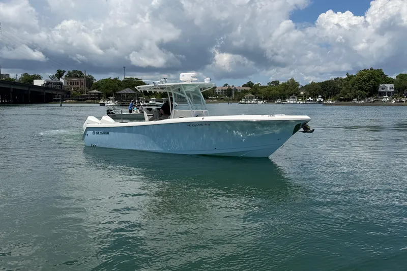 Slide: The Image of 2021 Sailfish 290 CC boat cruising on a calm waterway under a partly cloudy sky. - 12