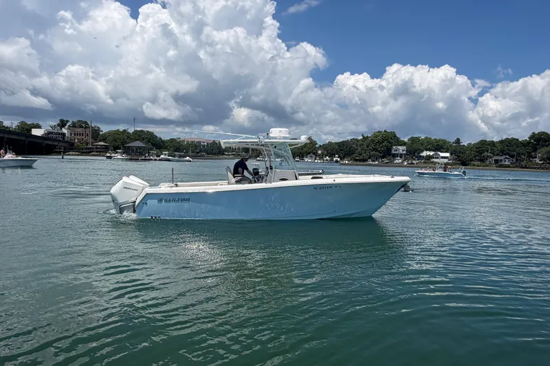 Slide: The Image of 2021 Sailfish 290 CC boat on calm water under a partly cloudy sky. - 13