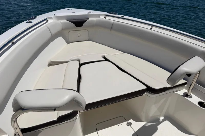 Slide: The Image of 2021 Sailfish 290 CC boat interior with cushioned seating, on calm water. - 17