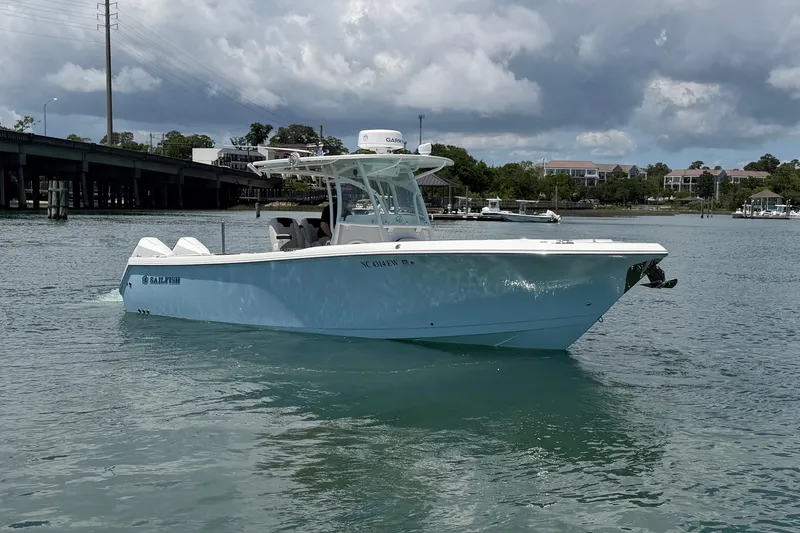 Slide: The Image of 2021 Sailfish 290 CC boat cruising on a calm waterway under a cloudy sky. - 2