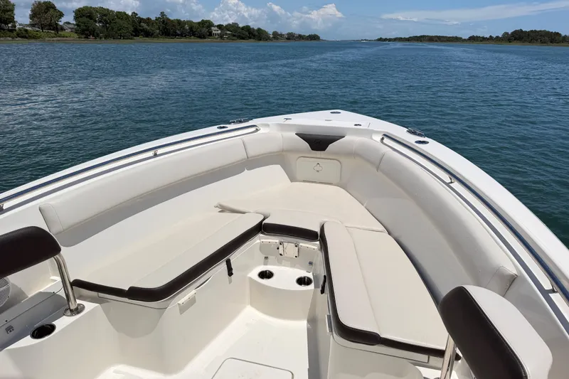 Slide: The Image of 2021 Sailfish 290 CC boat interior with cushioned seating on calm water. - 22