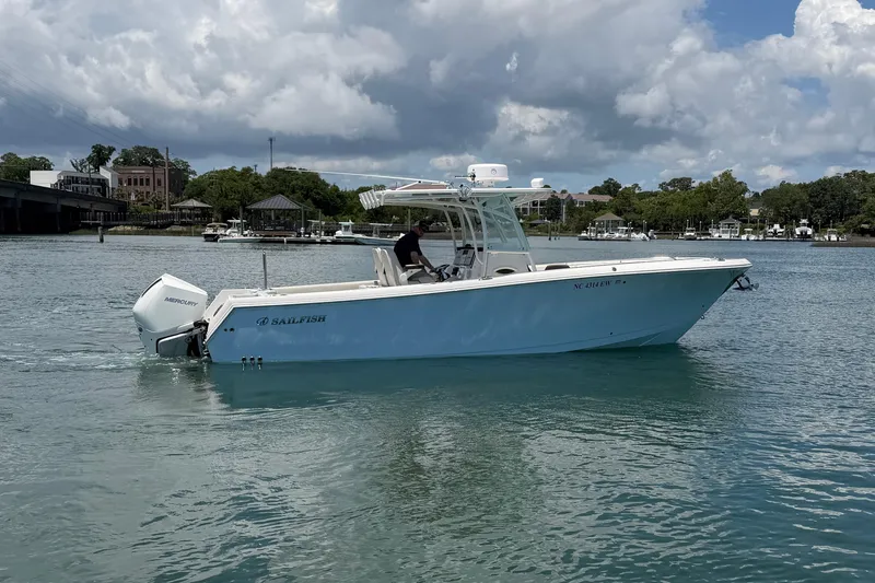 Slide: The Image of 2021 Sailfish 290 CC boat cruising on a calm waterway under a cloudy sky. - 4