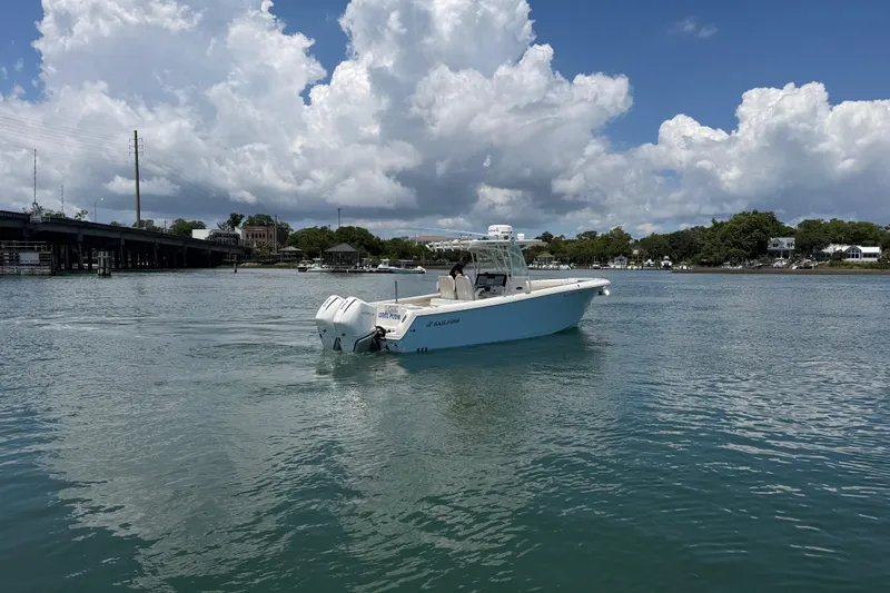 Slide: The Image of 2021 Sailfish 290 CC boat cruising on a calm waterway under a partly cloudy sky. - 6