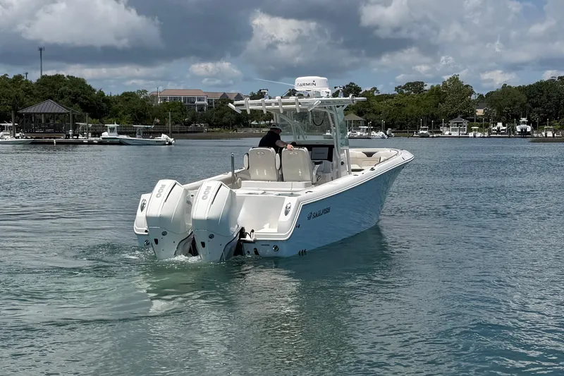 Slide: The Image of 2021 Sailfish 290 CC boat cruising on a calm lake under a cloudy sky. - 7