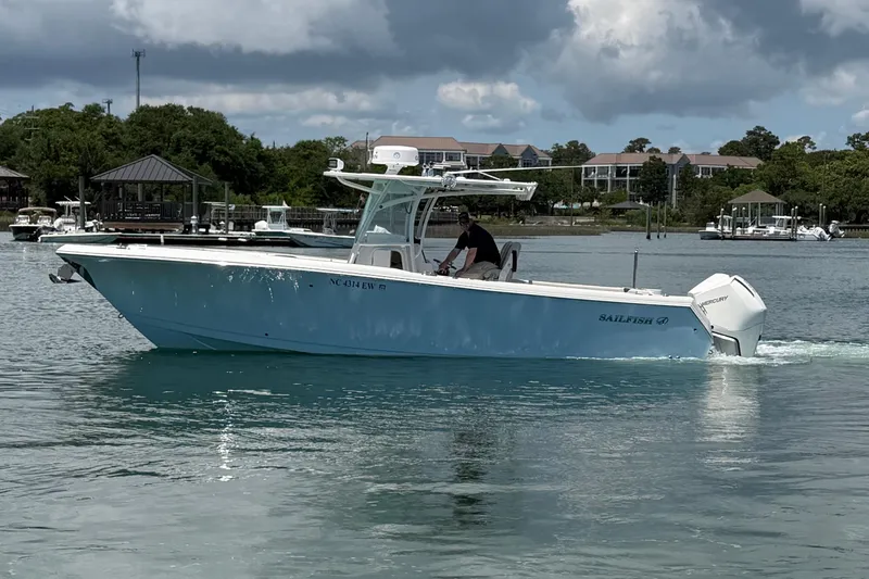 Slide: The Image of 2021 Sailfish 290 CC boat cruising on a calm waterway under cloudy skies. - 8