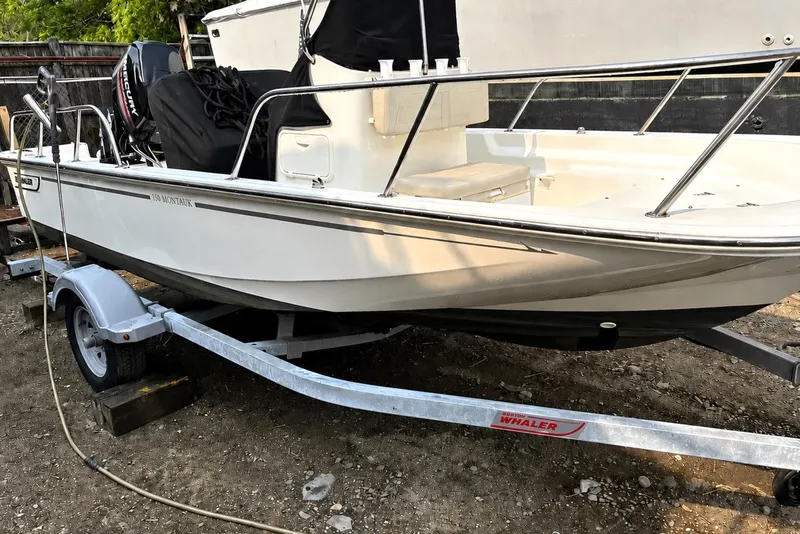 Slide: The Image of 2019 Boston Whaler 150 Montauk boat on trailer, parked outdoors. - 26
