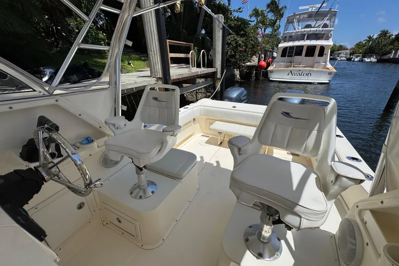 Slide: The Image of 2003 World Cat 270 EC boat interior with helm and seating, docked near waterway. - 14