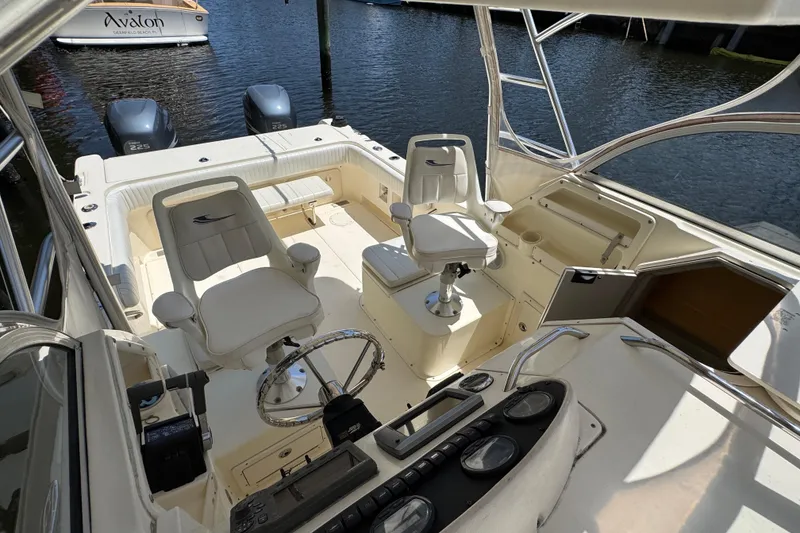 Slide: The Image of 2003 World Cat 270 EC boat interior with dual seats and steering wheel, docked by the water. - 15