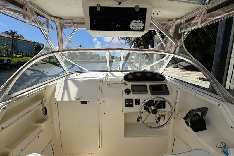 Slide: The Image of 2003 World Cat 270 EC boat cockpit with steering wheel and control panel, docked by a canal. - 16
