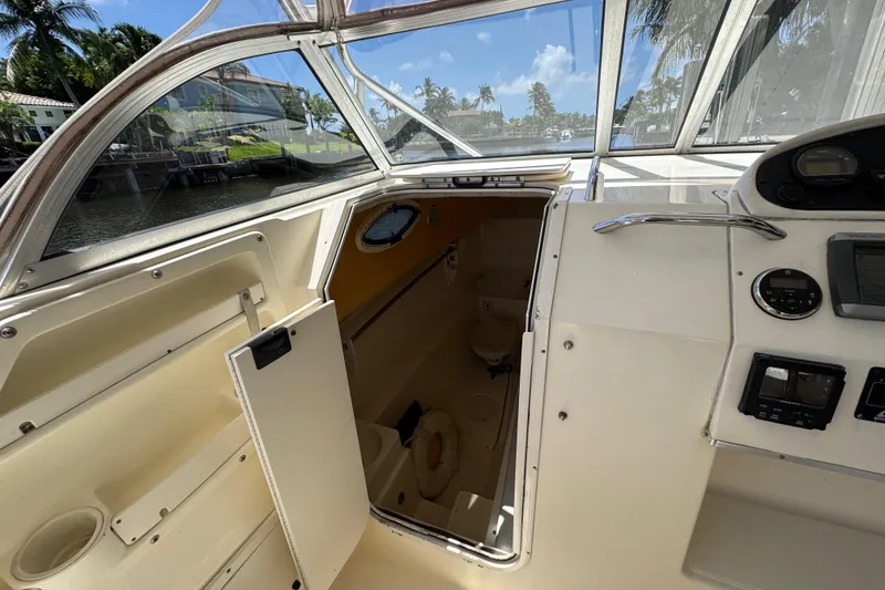 Slide: The Image of 2003 World Cat 270 EC boat interior with open cabin door, showcasing helm controls and seating. - 17