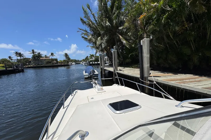 Slide: The Image of 2003 World Cat 270 EC boat docked by tropical waterfront with palm trees and clear blue sky. - 23