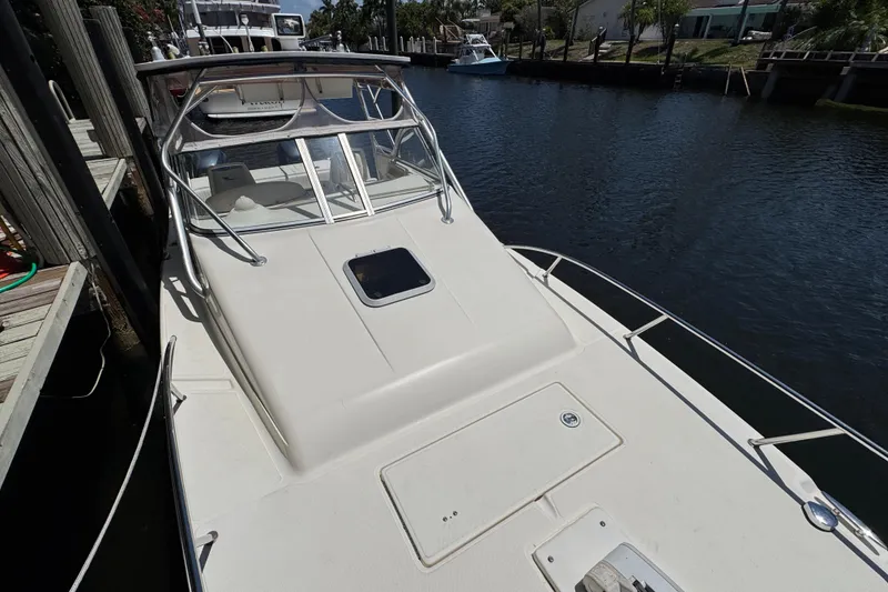 Slide: The Image of 2003 World Cat 270 EC boat docked by a canal, showcasing sleek design and spacious deck. - 27