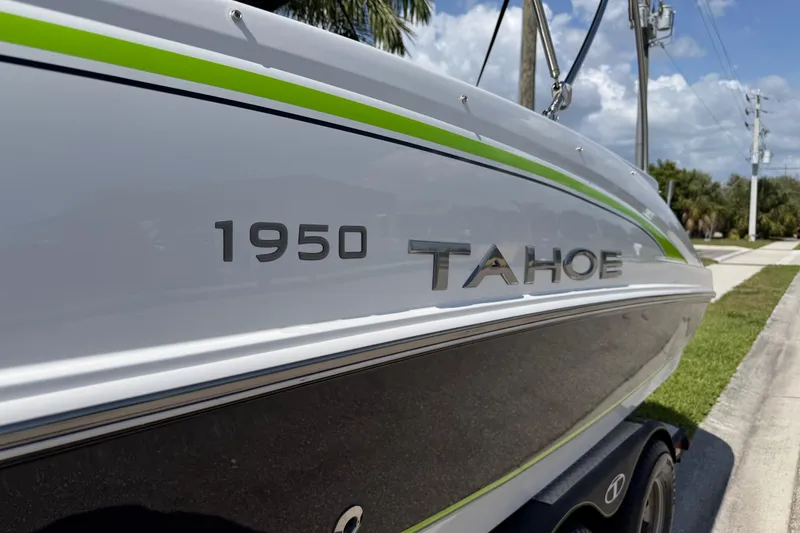 Slide: The Image of 2021 Tahoe 1950 boat with sleek design and green accent, parked on a sunny street. - 31
