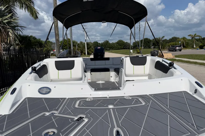 Slide: The Image of 2021 Tahoe 1950 boat with spacious seating and canopy, parked outdoors under a blue sky. - 25