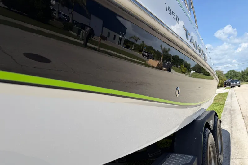 Slide: The Image of 2021 Tahoe 1950 boat on trailer, reflecting street and sky, with green accent stripe. - 32