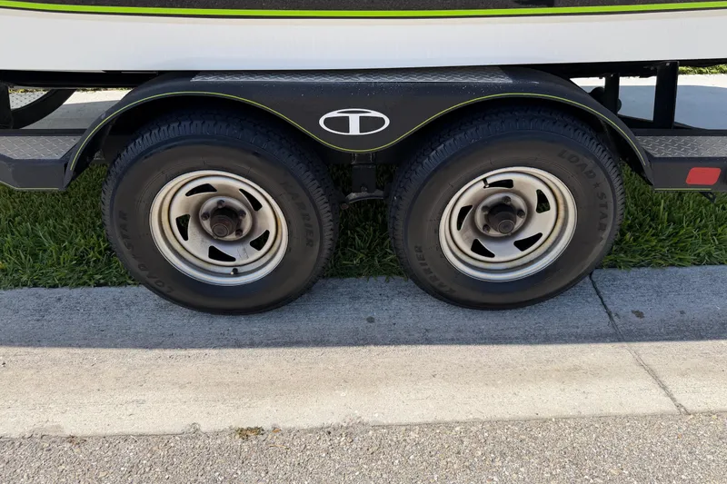 Slide: The Image of Trailer wheels of a 2021 Tahoe 1950 boat on a grassy surface. - 101