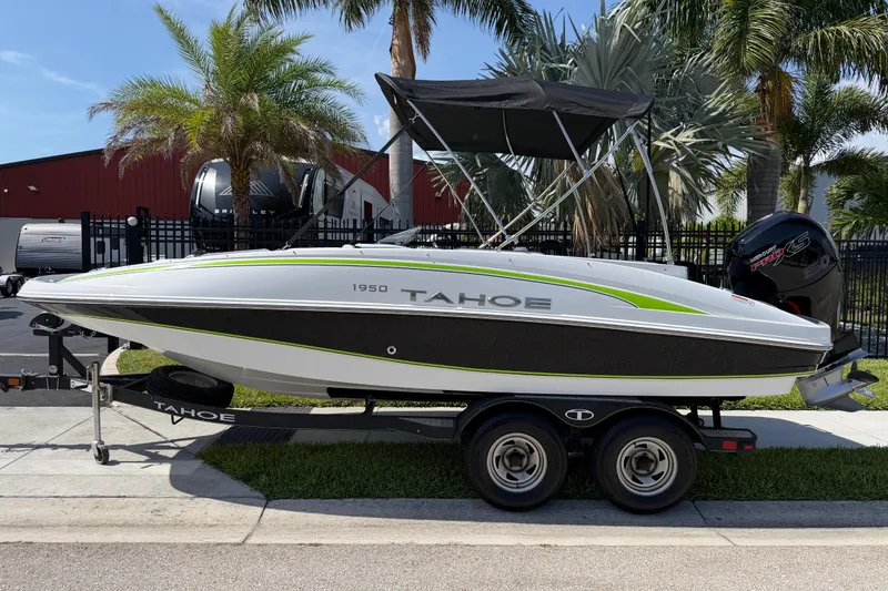Slide: The Image of 2021 Tahoe 1950 boat on trailer, parked near palm trees. - 2