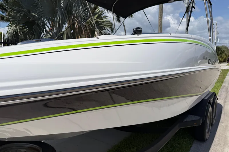 Slide: The Image of 2021 Tahoe 1950 boat with sleek design and green accents on a trailer. - 30