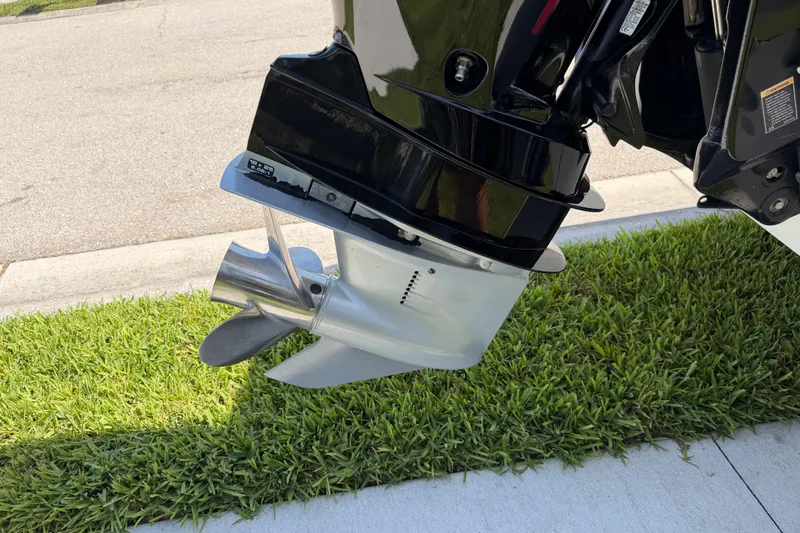 Slide: The Image of Outboard motor of a 2021 Tahoe 1950 boat on grass, showcasing propeller and lower unit. - 13