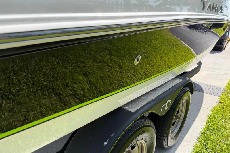 Slide: The Image of Close-up of a 2021 Tahoe 1950 boat on a trailer, reflecting green grass. - 16