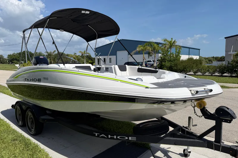 Slide: The Image of 2021 Tahoe 1950 boat on trailer with canopy, parked outdoors under blue sky. - 19