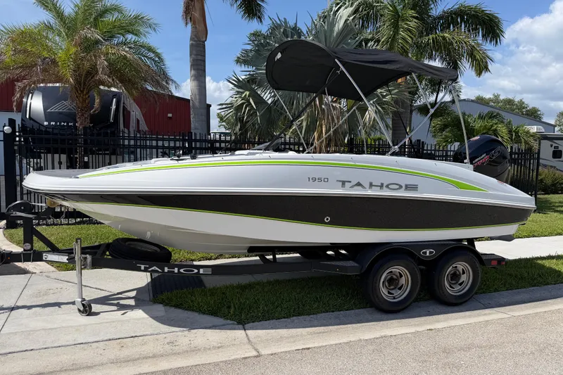 The Image of 2021 Tahoe 1950 boat on trailer, parked near palm trees under a clear sky. - 1