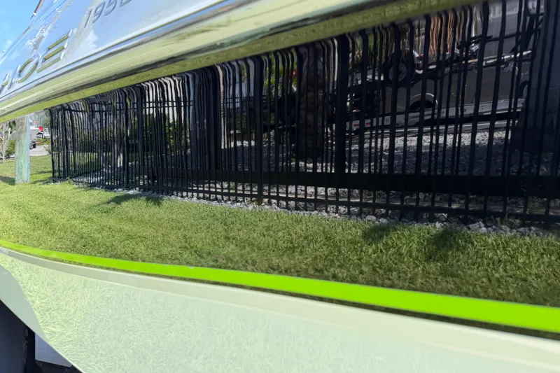 Slide: The Image of Reflective surface of a 2021 Tahoe 1950 boat, showing grass and fence reflection. - 20