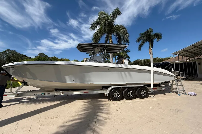 Slide: The Image of 2007 Spectre 34 boat on trailer, parked under palm trees, clear blue sky. - 12