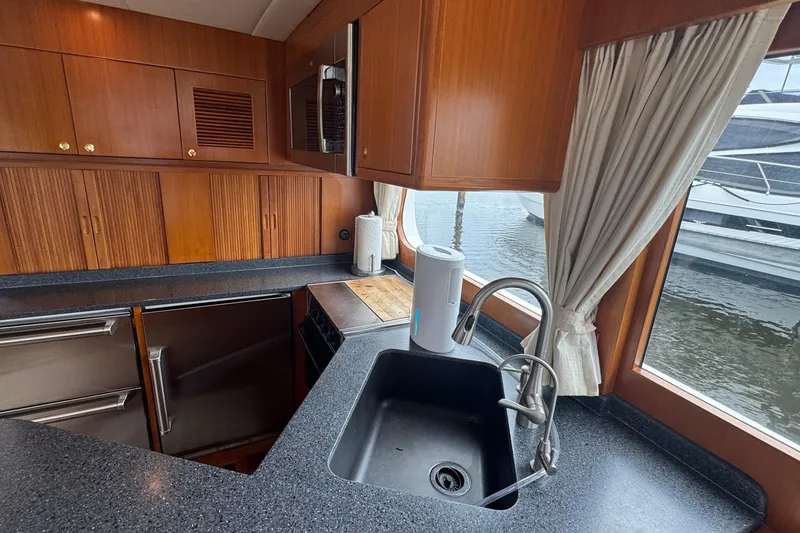 Slide: The Image of Luxurious kitchen interior of 2007 Jefferson Pilothouse 52 SE yacht with wood cabinetry and modern appliances. - 13