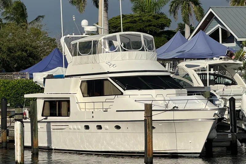 Slide: The Image of 2007 Jefferson Pilothouse 52 SE yacht docked with blue tents and palm trees in background. - 2