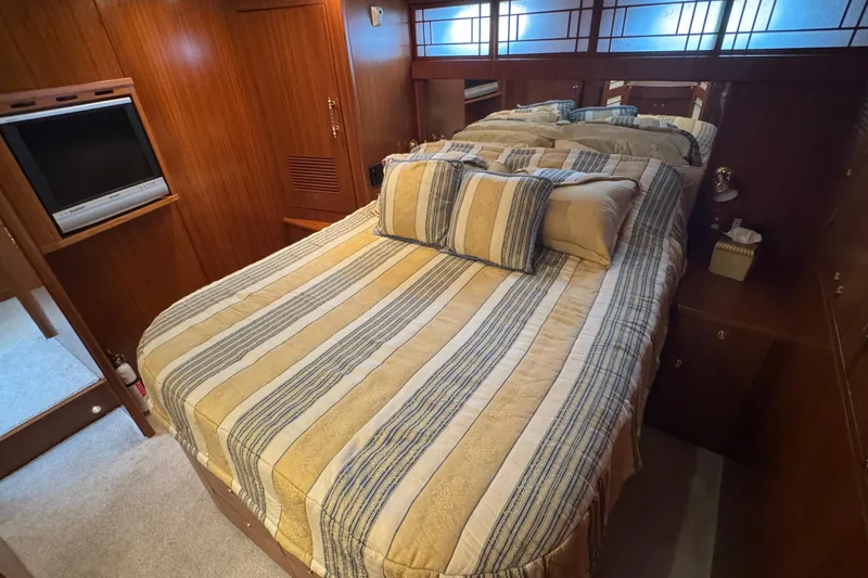 Slide: The Image of Cozy bedroom in 2007 Jefferson Pilothouse 52 SE yacht with striped bedding and TV. - 26