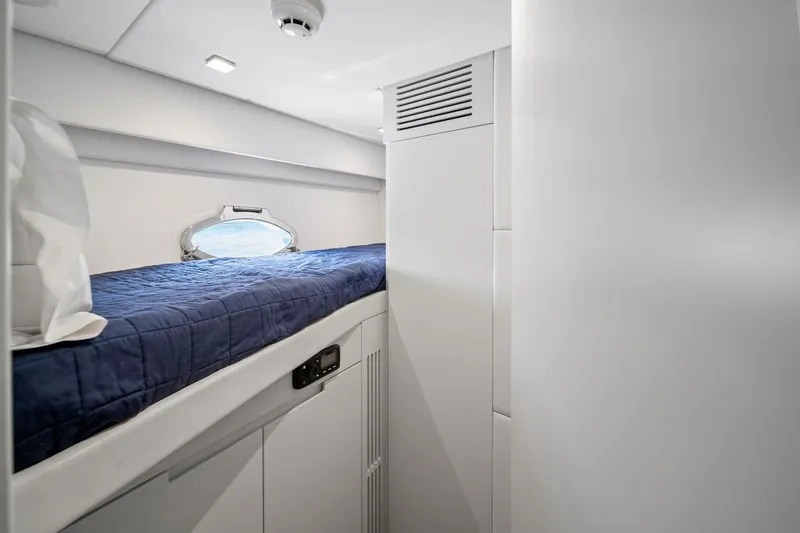 Slide: The Image of Interior cabin of 2021 Pershing 8X yacht with blue bedding and porthole window. - 42