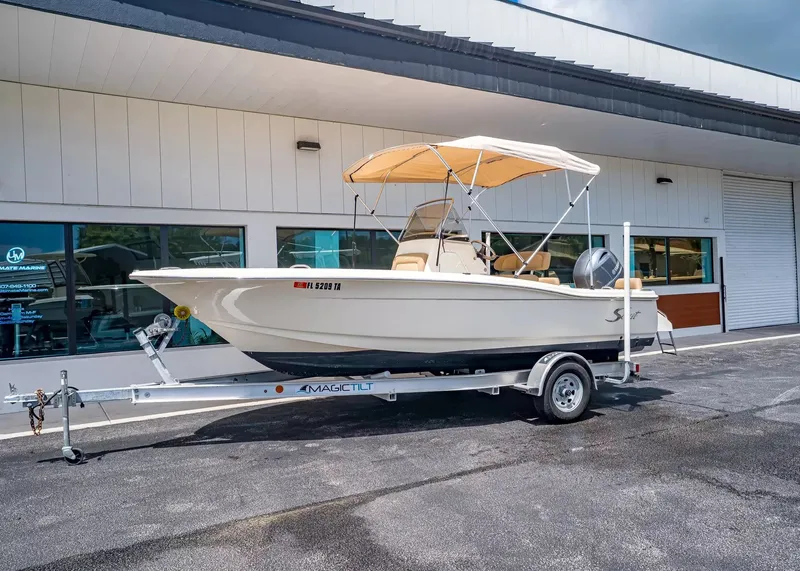 The Image of 2022 Scout 195 Sportfish boat on trailer outside building. - 1