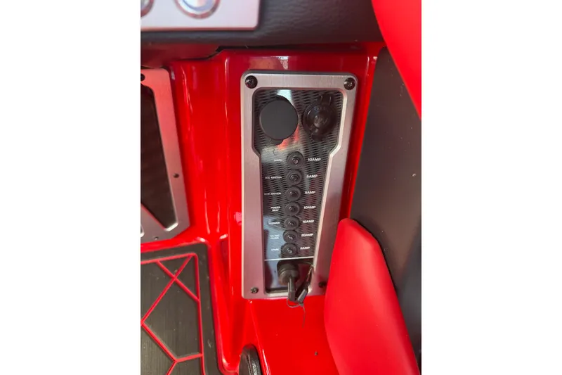 Slide: The Image of 2021 Malibu M220 boat interior control panel with red accents and switches. - 23