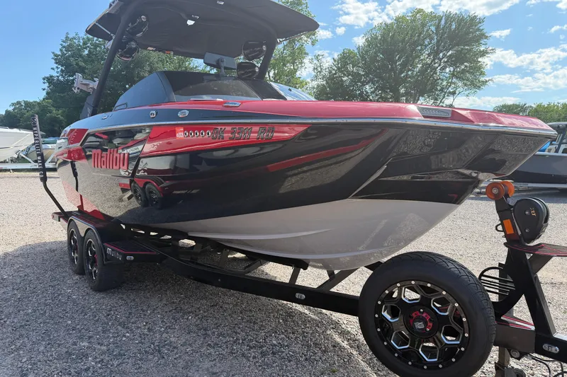 Slide: The Image of 2021 Malibu M220 boat on trailer, red and black design, parked outdoors. - 3