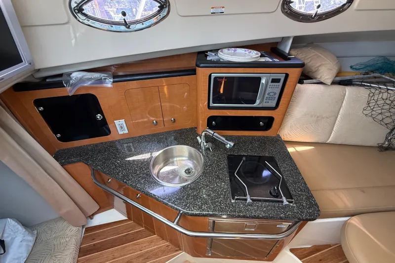 Slide: The Image of 2007 Robalo R305 Walkaround boat interior with kitchenette, sink, stove, and microwave. - 12