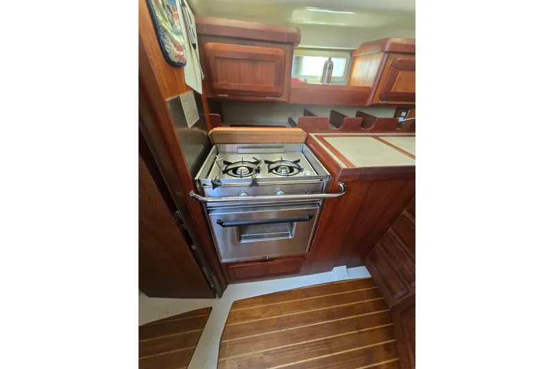 Slide: The Image of Compact kitchen area in a 1993 Hunter Legend 35.5 sailboat with wooden cabinetry and stove. - 15