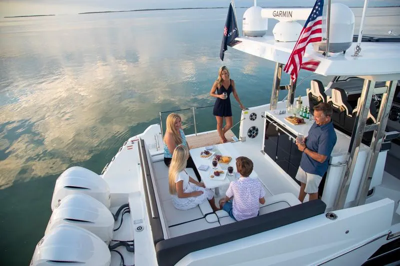 Slide: The Image of 2024 Jeanneau Leader 12.5 WA with people enjoying a meal on deck. - 11