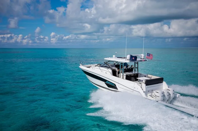 Slide: The Image of 2024 Jeanneau Leader 12.5 WA cruising on clear turquoise waters under a partly cloudy sky. - 5