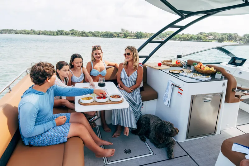 Slide: The Image of Family enjoying a meal on a 2026 Jeanneau TH33 yacht, with scenic water views. - 8