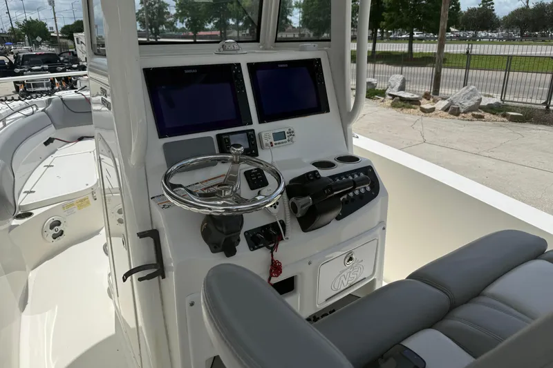 Slide: The Image of 2021 NauticStar 2602 Legacy boat helm with dual screens and steering wheel. - 12