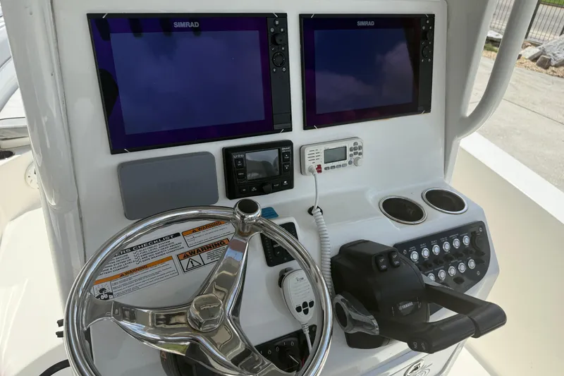 Slide: The Image of 2021 NauticStar 2602 Legacy boat dashboard with dual Simrad displays and steering wheel. - 19