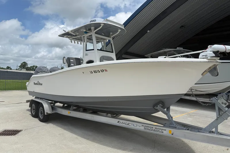 Slide: The Image of 2021 NauticStar 2602 Legacy boat on trailer, parked outdoors under cloudy sky. - 3