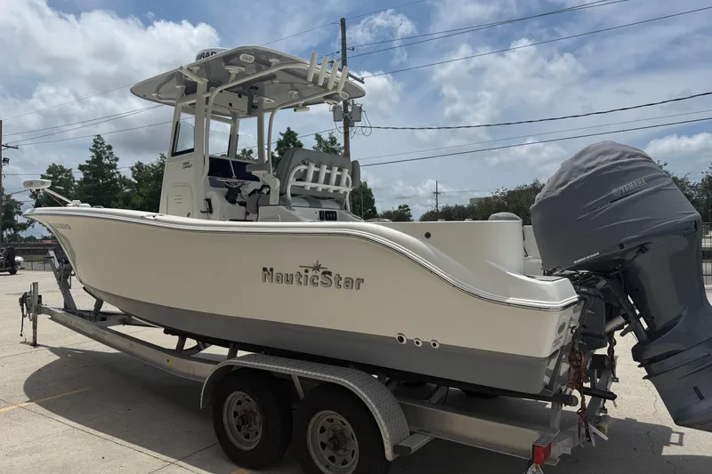 Slide: The Image of 2021 NauticStar 2602 Legacy boat on trailer, parked outdoors under cloudy sky. - 6