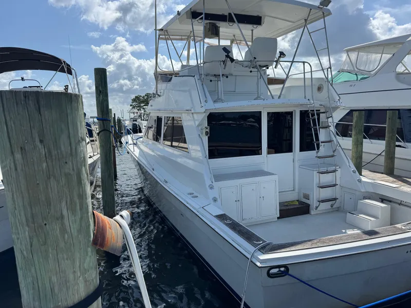 The Image of 1982 Viking 46 Convertible yacht docked at marina under a partly cloudy sky. - 0