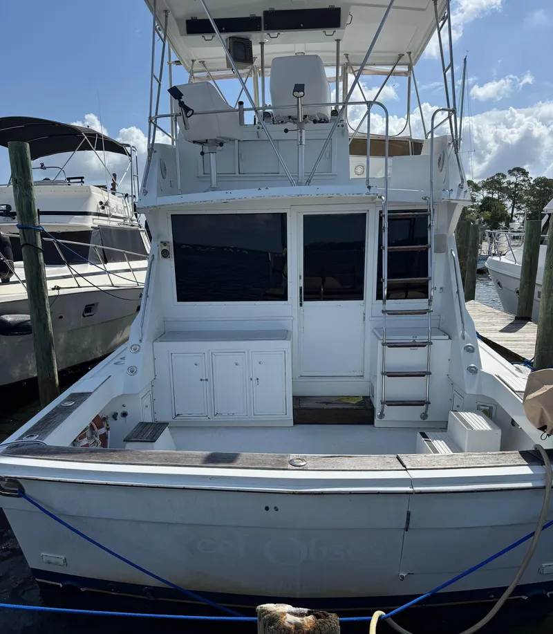 Slide: The Image of 1982 Viking 46 Convertible yacht docked at marina, rear view with ladder and seating area. - 4