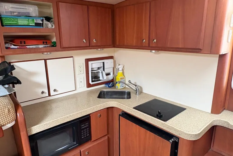 Slide: The Image of 2004 Luhrs 30 Open yacht kitchen with wooden cabinets, sink, stove, and microwave. - 11