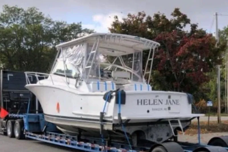 Slide: The Image of 2004 Luhrs 30 Open boat named "Helen Jane" on a trailer, surrounded by trees. - 2