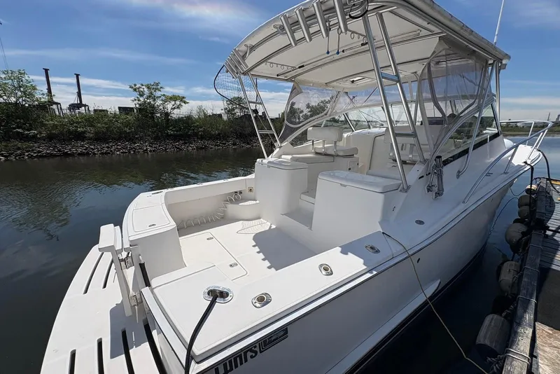 Slide: The Image of 2004 Luhrs 30 Open boat docked, featuring spacious deck and canopy under clear skies. - 4