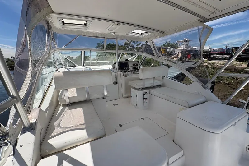 Slide: The Image of 2004 Luhrs 30 Open boat interior with seating and helm, docked under clear skies. - 6